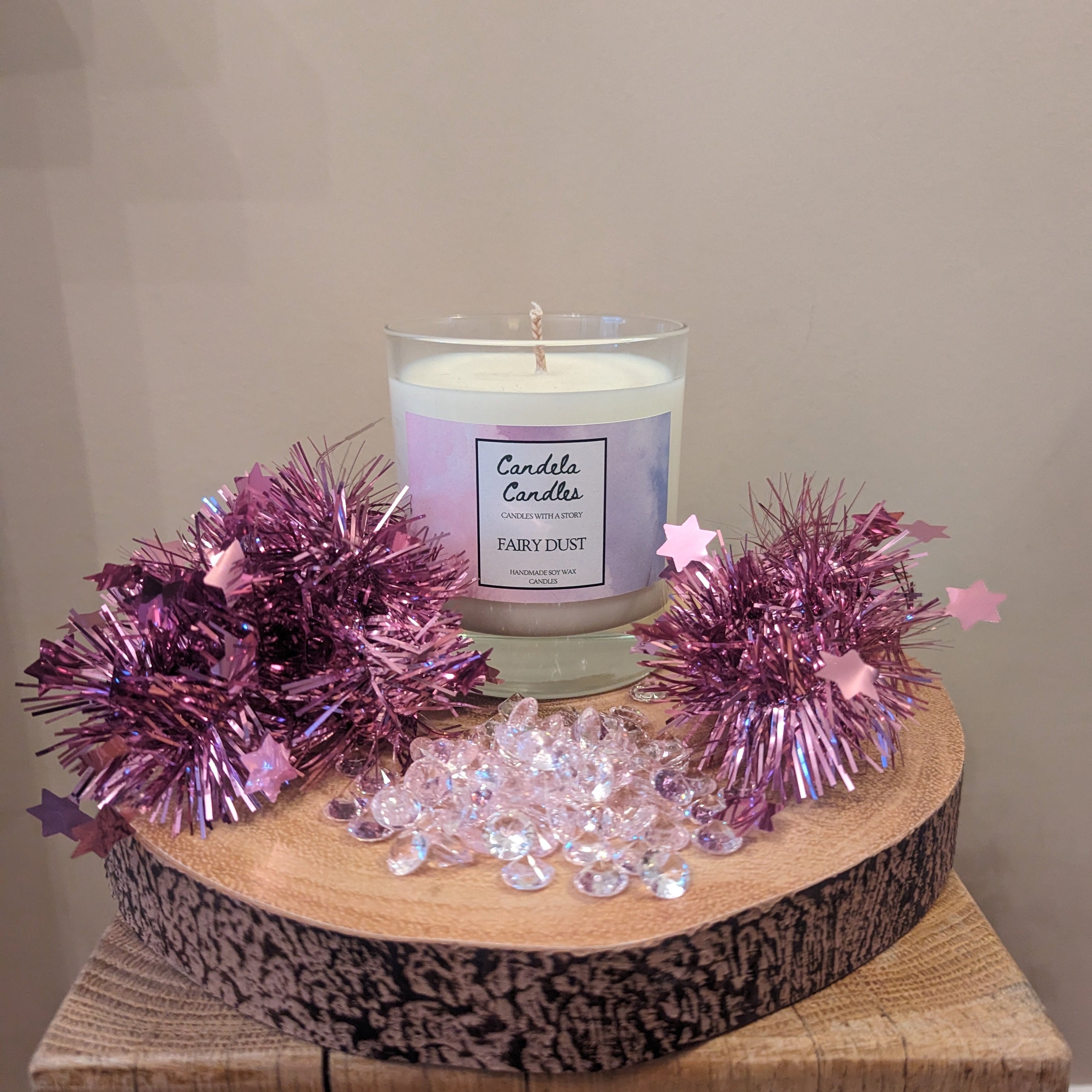 Candle on a wooden stand with decorative purple tinsel and crystals