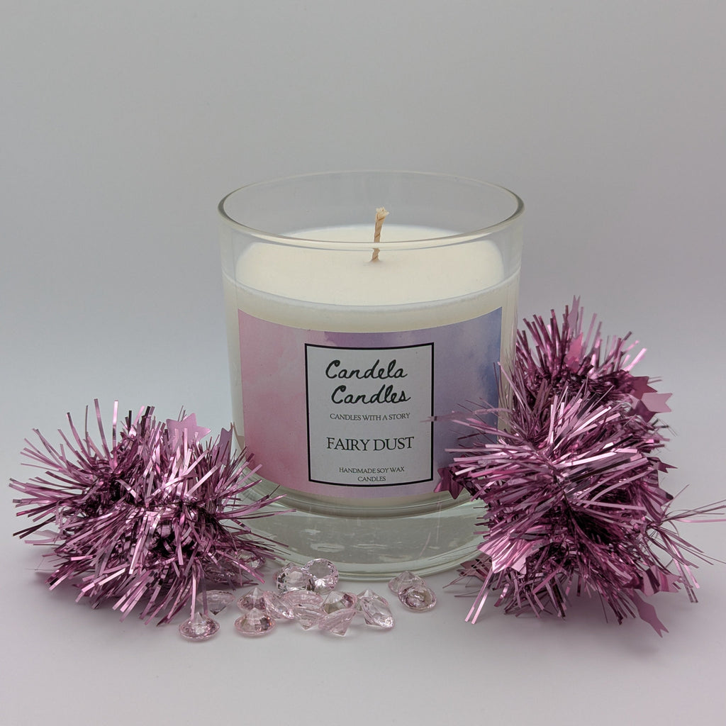 Candle with 'Candela Candles' label and pink decorative elements on a light gray background