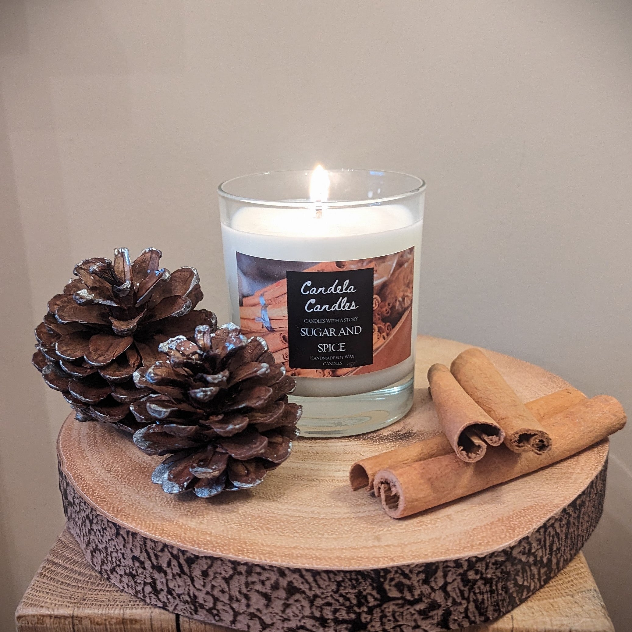 Candle with cinnamon sticks and pine cones on a wooden surface