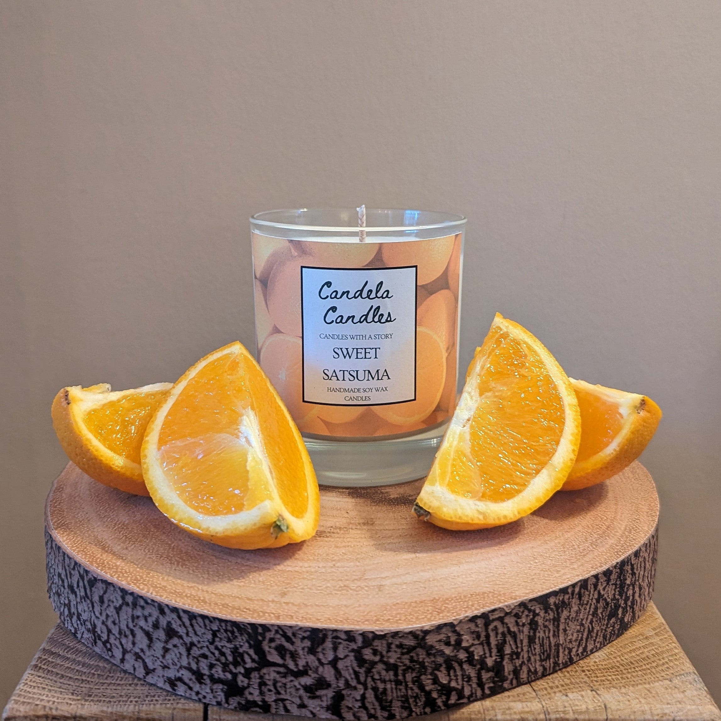Candle labeled 'Sweet Satsuma' with orange slices on a wooden surface