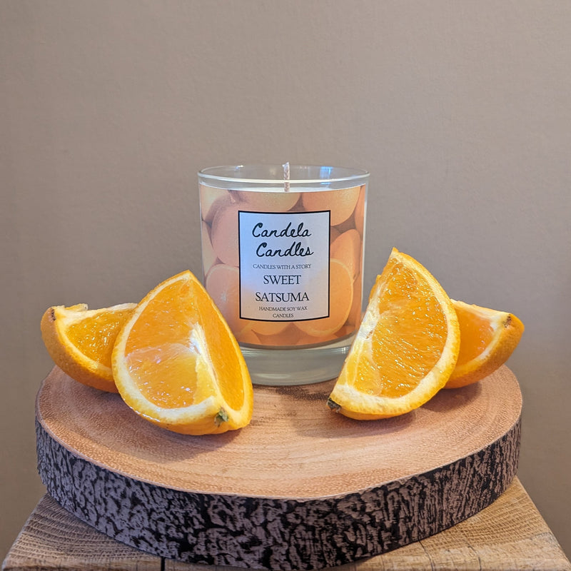 Candle labeled 'Sweet Satsuma' with orange slices on a wooden surface